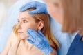 Cosmetology Service. Young woman at beauty clinic lying while doctor in gloves touching cheek looking at skin back view