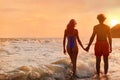 Young woman in bikini and her on beach at sunset. Lovely couple