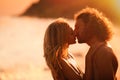 Young woman in bikini kissing her on beach at sunset. Lovely couple