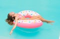 Young women in bikini lying down on an inflatable donut in swimming pool. Girl enjoys sunbathing on floating pool inflatable toy o