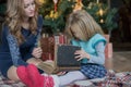 Mom and daughter spend leisure time reading a book at the Christmas tree