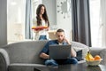 Young woman bringing breakfast to her busy husband at home.