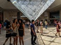 Young women check selfie shots in front of upside down pyramid in Louvre Carrousel