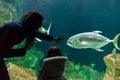 Young woman with child watch a fish in aquarium