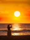 Young women come to travel to relax at the sea on vacation using A smartphone takes pictures of the sunset silhouette alone in the Royalty Free Stock Photo