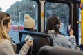 Young women communicate with their mobile devices on bus