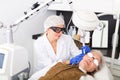 Cosmetologist using laser to resurface skin of mature woman& x27;s face