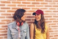 Young women couple looking and smiling each other in a brick wall background. Same sex happiness and joyful scene