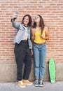 Young women couple making a selfie. Behind brick wall. Positive emotion and tolerance concept