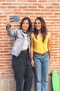 Young women couple making a selfie. Behind brick wall. Positive emotion and tolerance concept