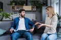 A young woman demands money from her husband, the man does not show empty pockets. At home, sitting on the couch. Quarrels, Royalty Free Stock Photo