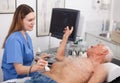 Woman examination elderly man at abdomen with ultrasonography device