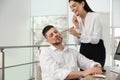 Young woman drawing on colleague`s face while he sleeping in office. Funny joke Royalty Free Stock Photo