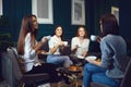 Women drink coffee laughing at a meeting of friends at home.