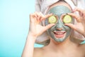 Young women with facial masks and cucumber slices isolated over studio blue wall Royalty Free Stock Photo