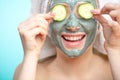 Young women with facial masks and cucumber slices isolated over studio blue wall Royalty Free Stock Photo