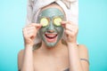 Young women with facial masks and cucumber slices isolated over studio blue wall Royalty Free Stock Photo