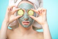 Young women with facial masks and cucumber slices isolated over studio blue wall Royalty Free Stock Photo