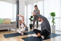 Young woman fitness and yoga instructor helping couple in their home for workout exercises. Female coach working with clients