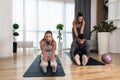 Young woman fitness and yoga instructor helping couple in their home for workout exercises. Female coach working with clients