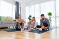 Young woman fitness and yoga instructor helping couple in their home for workout exercises. Female coach working with clients