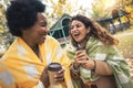 Young women friends chatting outdoors and drinking coffee while enjoying the walk in the park together Royalty Free Stock Photo