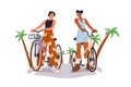 Young women friends riding bicycles together. Happy girls couple on active tropical holiday, cycling on bikes, talking Royalty Free Stock Photo