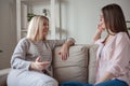 Young women friends talking, smiling together, sitting on sofa at home Royalty Free Stock Photo