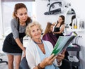 Hairdresser with senior woman choosing hairstyling in magazine