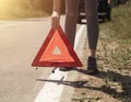 Young women hands close up putting triangle caution sign on road near broken car on roadside Royalty Free Stock Photo