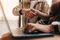 Young women handshake with friends after agreeing to work together at coffee shop