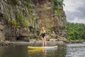 Young women Having Fun Stand Up Paddling in the sea. SUP. Red hair girl Training on Paddle Board near the rocks Royalty Free Stock Photo