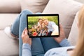 Young woman having remote conversation with happy family on picnic, using tablet computer at home Royalty Free Stock Photo