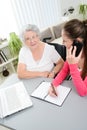 Young woman helping an old senior woman doing paperwork and administrative procedures with laptop computer at home Royalty Free Stock Photo