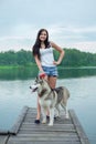 Young women and her dog husky resting near lake in summer