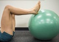 Young women with her feet up on a green exercise ball