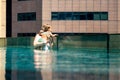 Young woman with her little daughter in the pool on the roof of a skyscraper in a metropolis look overboard