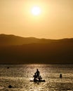 Young women with her two kids practicing paddle surf during the sunset