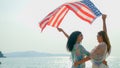 young women hold American flags on the beach and the sea on their summer vacation and they smile and enjoy their vacation Royalty Free Stock Photo