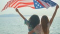 young women hold American flags on the beach and the sea on their summer vacation and they smile and enjoy their vacation Royalty Free Stock Photo