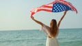 young women hold American flags on the beach and the sea on their summer vacation and they smile and enjoy their vacation Royalty Free Stock Photo