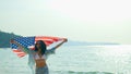 young women hold American flags on the beach and the sea on their summer vacation and they smile and enjoy their vacation Royalty Free Stock Photo