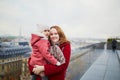 Young woman holding adorable todler girl while enjoying the view from Parisian rooftop terrace