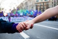 Young women holding hands during woman`s day rally with purple balloons in background for women rights and feminism