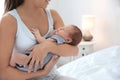 Young woman holding her baby near breast in bedroom Royalty Free Stock Photo