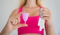 Young woman holding at her hands menstrual cup and tampons