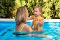 Young woman instructor learning little girl to swim in a pool Royalty Free Stock Photo