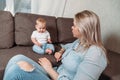 Young woman and little baby boy at home on bed. Mom teaches a small child to perceive criticism