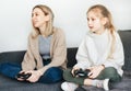 Young women and little girl joyful playing video games with controller console