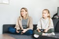 Young women and little girl joyful playing video games with controller console